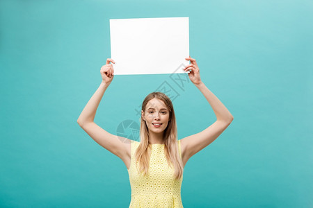 肖像美丽的年轻causin女人拿着一张空白纸孤立在面贴蓝色背景上肖像孤立在面贴蓝色背景上图片