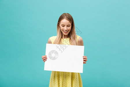 美丽的女人带着一张空白的广告牌隔着蓝背景白的广告牌蓝背景图片