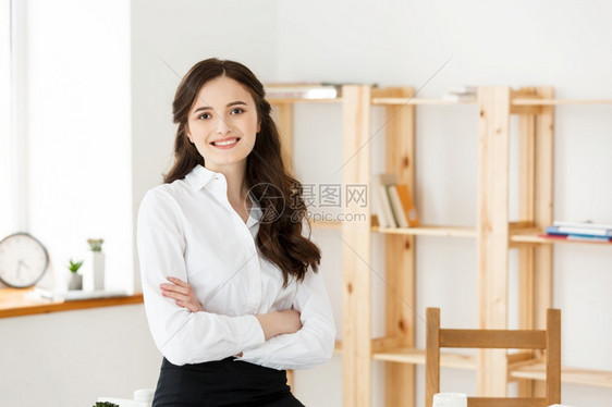笑着的成年职业女商人手交叉坐在办公室的桌子上笑着成年职业女商人图片