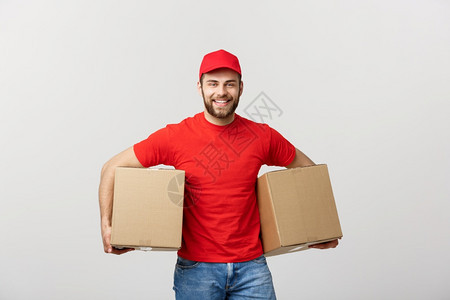 交付概念笑的英俊causin送货员拿着纸盒孤立于灰色背景图片