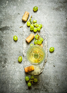 酒杯上装有管子和白葡萄的酒杯放在石板上酒杯装有管子和白葡萄的酒杯图片