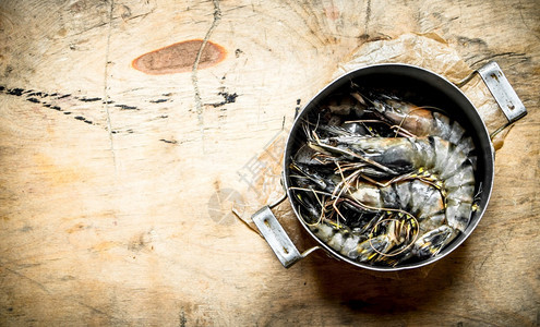 虎虾在一个旧的酱盆里木制背景虎虾在一个旧的酱盆里图片