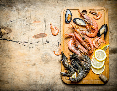 新鲜海产食品虾贝类和柠檬的切割板木制背景新鲜海产食品贝类和柠檬的切割板以及虾贝类和柠檬的切割板图片