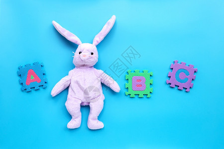 蓝背景上带有英文字母拼图的兔子玩具教育概念复制空间图片