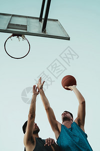 青年篮球运动员在户外法庭上一对地打球体育和篮概念图片