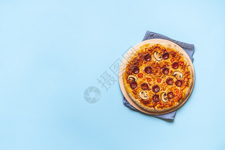 披萨上美味的辣椒尼披萨烤箱新鲜的披萨蓝色无缝背景平躺着准备吃披萨真正的意大利菜图片