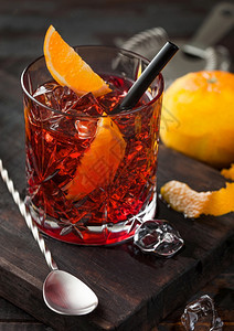 白葡萄鸡尾酒在水晶玻璃中橙色切片在肉板上勺子在木制背景上图片