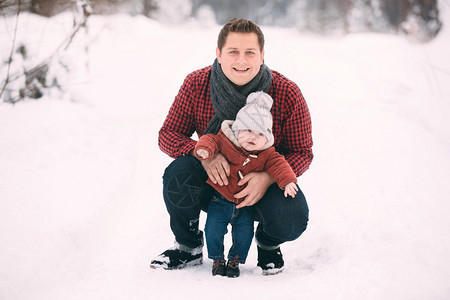 年轻的爸爸和宝宝在雪地里玩耍图片