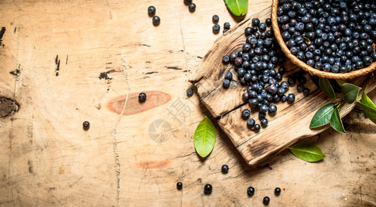 野生水果野生蓝莓在有叶子的杯里在木制桌上野生蓝莓在有叶子的杯里在木制桌子上背景