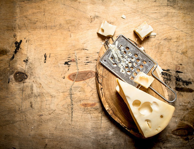 一块奶酪和板上的磨刀放在木制桌子上图片