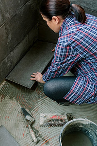 在露台铺新瓷砖地板的女建筑工图片