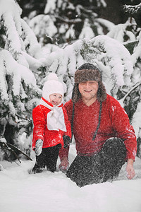 快乐的小女孩穿着红色大衣父亲在冬季森林里玩雪女孩和爸一起玩在冬天森林里玩雪图片