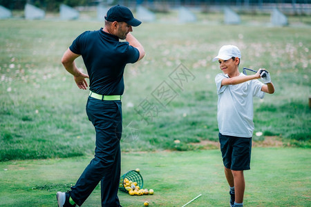 一个高尔夫教练和一个男孩在练习高尔夫图片