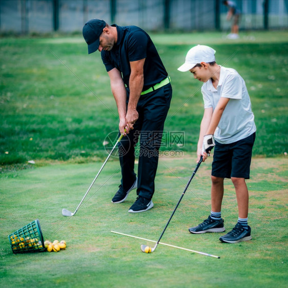一个高尔夫教练和一个男孩在高尔夫练习场上图片