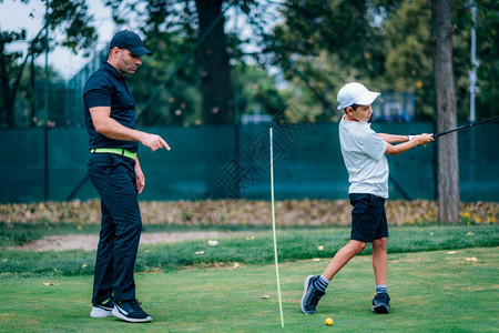 个人训练高尔夫教小男孩打高尔夫图片
