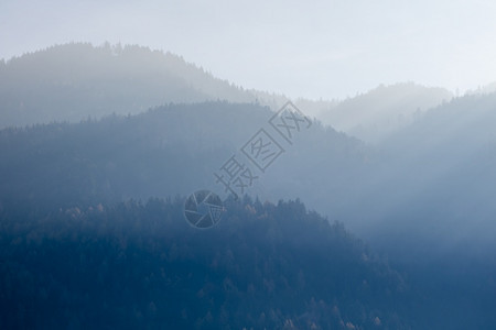 来自模糊的雾山美丽宁静风景树木在库夫斯坦奥特里亚阳光明媚的天空下背景图片