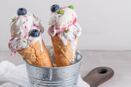 甜冰淇淋品配有新鲜蓝莓和百草枯叶背景图片