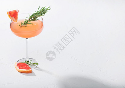 现代豪华马提尼杯的红葡萄酒鸡尾白底带有迷迭香和水果片图片