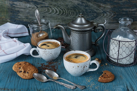 家庭早餐两杯咖啡加牛奶和自制燕麦饼干在蓝色木制旧餐桌上加巧克力土制风格低键图片