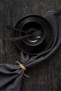 空黑厨房用具的创作构件餐具和用叉子勺在同样彩色背景上为纺织品餐巾提供具和复制空间顶部视图以黑颜色为餐桌提供具和巾纸图片