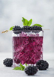 清凉的夏季鸡尾酒黑莓装在晶玻璃中冰块和薄荷装在光背景上苏打汽水和酒精混合图片
