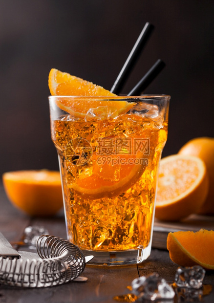 在高球玻璃中用橙色片和黑底的冰块来装有aperolsitz夏季鸡尾酒图片