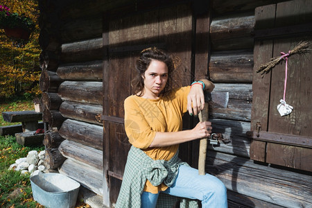 山上一座木屋附近拿着斧子的女孩背景图片
