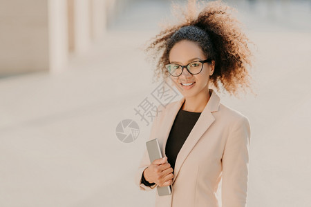 美籍女商人在户外漫步带着触摸板穿正规衣服戴光观眼镜在头上微笑会后享受闲暇时间图片