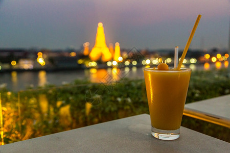 在bangkothailnd的美丽日落时watrun寺庙的新鲜芒果汁和全景空中观察背景图片