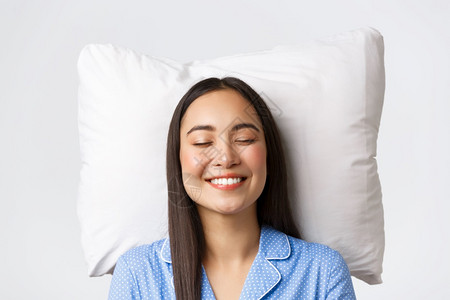 睡在枕头上穿着蓝睡衣闭上眼睛微笑白梦或夜间睡觉想象一些可爱白色的背景躺在枕头上白色的背景图片