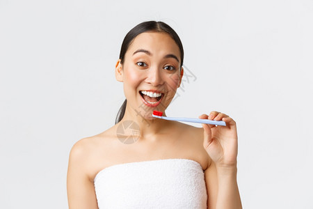 美丽个人照顾和卫生概念热情快乐的亚洲女在浴巾上准备刷白牙持有笑脸白色背景美丽持有牙刷和笑脸白色背景图片