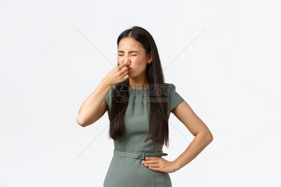 小商主女企业家概念令人厌恶的像亚洲女穿着优雅的裙子用手指闭上她的鼻子从肮脏臭味站立的白色背景中严酷地闭上她的鼻子小商主女企业家概图片