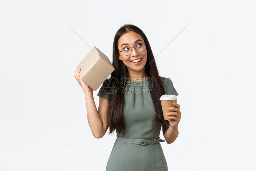 好奇地接受网上商店的包裹站着白色背景好奇地笑着女喝咖啡握着杯子和摇篮试图猜测里面有什么看着好奇站白色背景图片