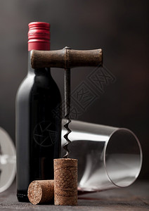 在木本底有玻璃和一瓶红葡萄酒的老旧软木瓶子图片