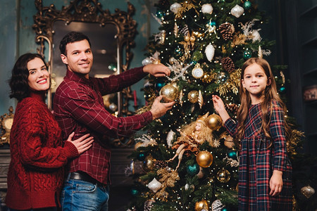 夫妇和女儿在圣诞树前开心的合照图片