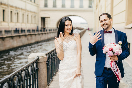 可爱的新婚夫妇在手指上展示戒很高兴有婚礼穿着纱在桥上行走有良好的关系人和婚姻概念图片