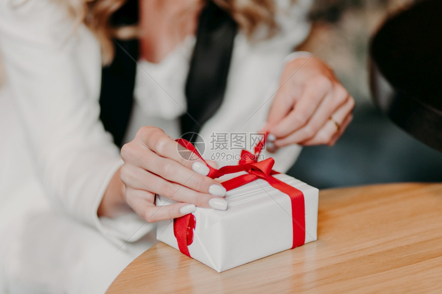 无法辨认的天主教女照片红丝带绑在小白色礼物盒上给某人准备惊喜在发香新年或生日模糊的背景上图片