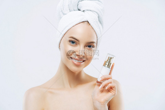 美容概念丽的微笑着女士在室内装上化妆品皮肤健康头部包着毛巾享受复健治疗图片