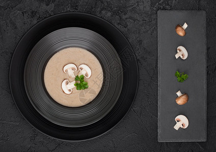 黑餐厅盘子底蘑菇汤石板和新鲜蘑菇图片