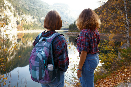 山湖和地背景的两位快乐女孩图片
