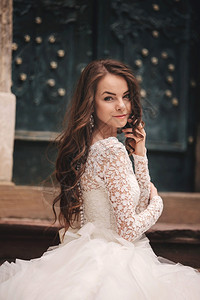 穿着白色婚纱的美丽年轻新娘肖像穿着白色婚纱长发在旧的欧洲城靠近旧建筑的女人结婚日穿着白色婚纱的美丽年轻新娘肖像在旧欧洲城长发白色图片