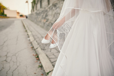身着婚纱和面的新娘带着鞋子走在街上图片