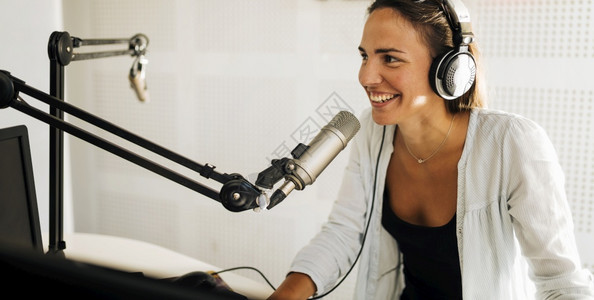 穿戴耳机的有吸引力年轻妇女在线广播电台脱口秀上讲话图片