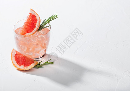 清凉的夏季红葡萄酒鸡尾在晶玻璃中装有冰水果片和迷迭香在白色背景和深影上装有冰水果片和迷迭香图片