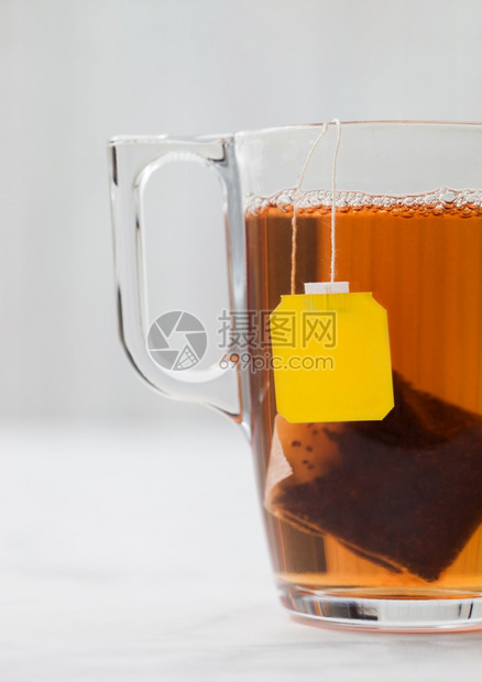 黄色标签黑茶叶袋白背景的清晰玻璃杯图片