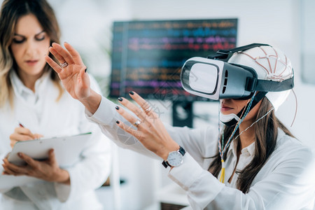 在神经科学实验室的医生中女病人身穿Vr或虚拟现实护目镜图片