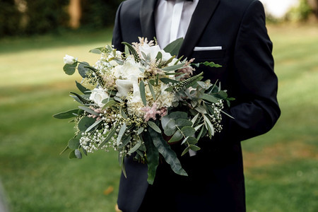 时尚的新郎拿着娘花束婚礼在人手里图片