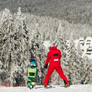 滑雪教练和小男孩一起滑雪图片
