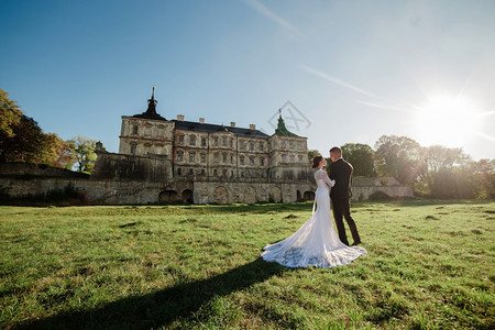 在城堡旁的草地上拍婚纱照的夫妻图片