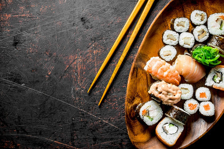 不同种类的寿司卷子和木板上的深色生锈背景卷子和木板上的背景图片